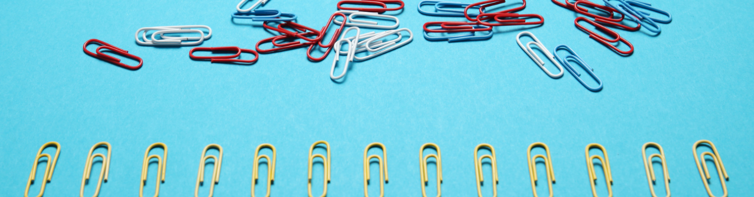 A line of paper clips below a scattered and disorganized heap of paper clips