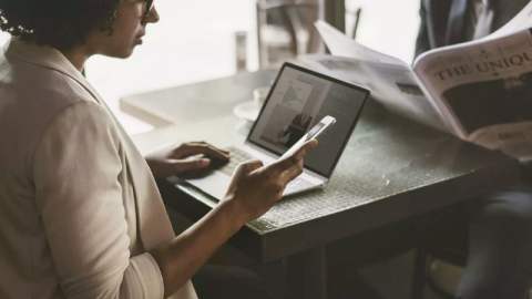 A women with a mobile pone and laptop in coworking space